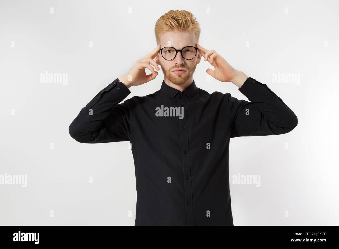 Jeune homme dans le processus de pensée.Gros plan à barbe rouge en chemise noire, les lunettes se concentrent sur la création d'une idée de démarrage isolée sur le backgroun gris Banque D'Images