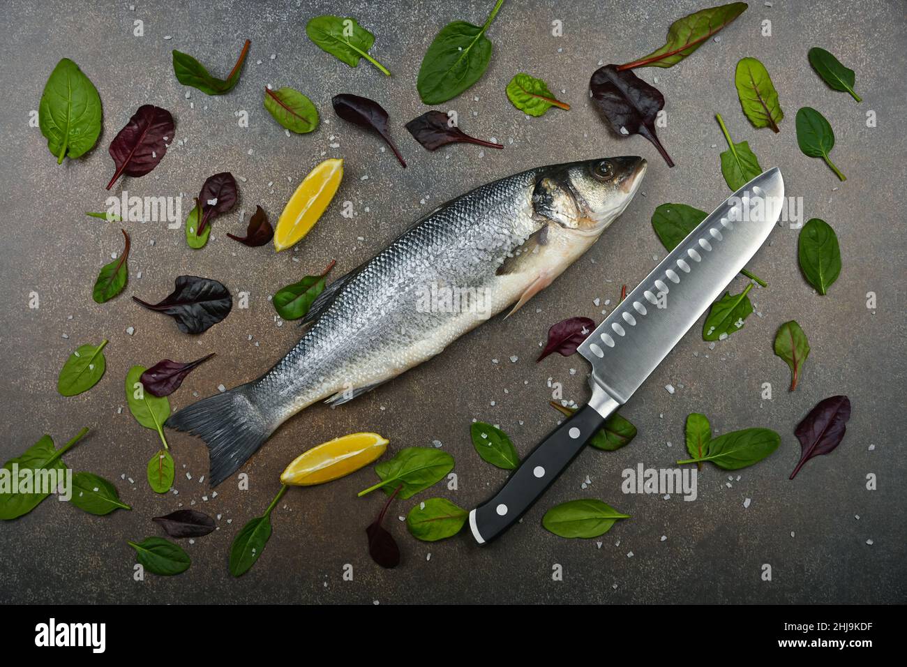 Gros plan sur une table de poisson frais de mer européen cru, avec un couteau de cuisine, des quartiers de citron et des feuilles de salade, vue en hauteur sur le dessus,directement au-dessus Banque D'Images