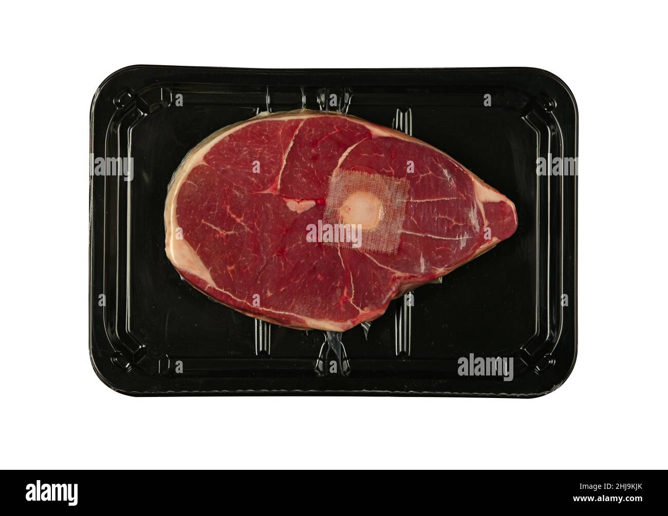 Gros plan de viande d'agneau ou de mouton ossobuco ou de tige de buco d'osso scellé sous vide avec film plastique noir , isolé sur fond blanc, vue de dessus en hauteur, Banque D'Images