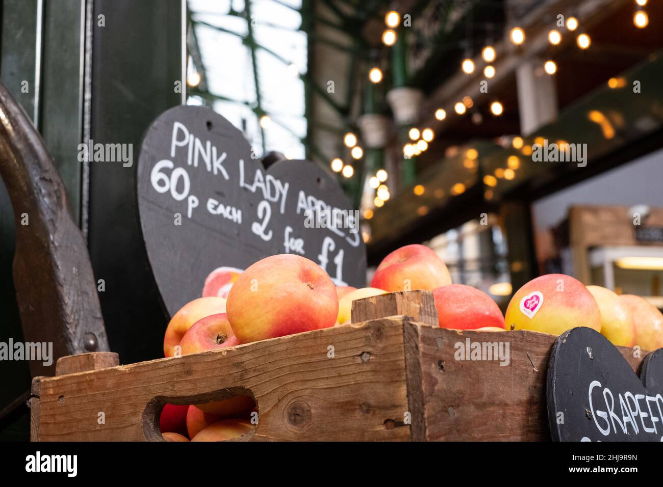 Borough Market, marché urbain couvert à Southwark, dans l'est de Londres, avec une large gamme d'étals alimentaires.Caisse en bois avec pommes Pink Lady au premier plan Banque D'Images