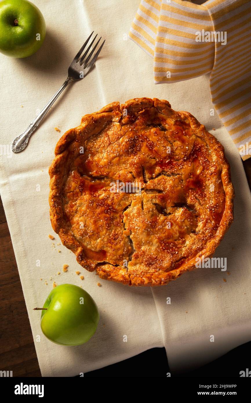 Une tarte aux pommes de Thanksgiving maison chaleureuse avec une fourchette assise sur un plan d'examen rustique en bois. Banque D'Images