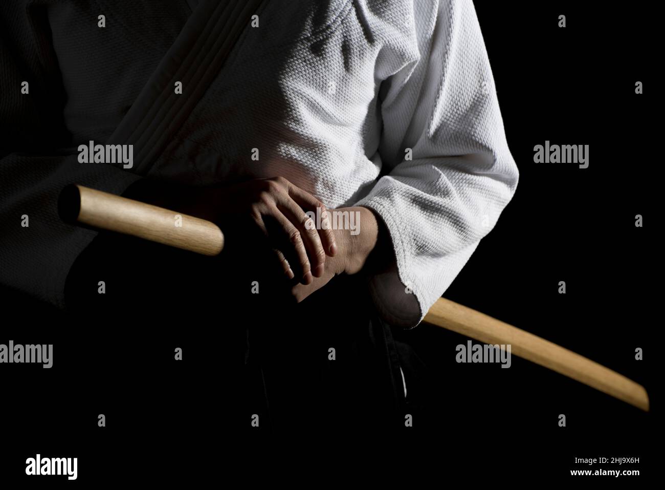 Aikido hakama, uniforme des arts martiaux japonais sur fond noir.Faible profondeur de champ.SDF.Une fille en hakama noir debout dans la posture de combat avec W Banque D'Images