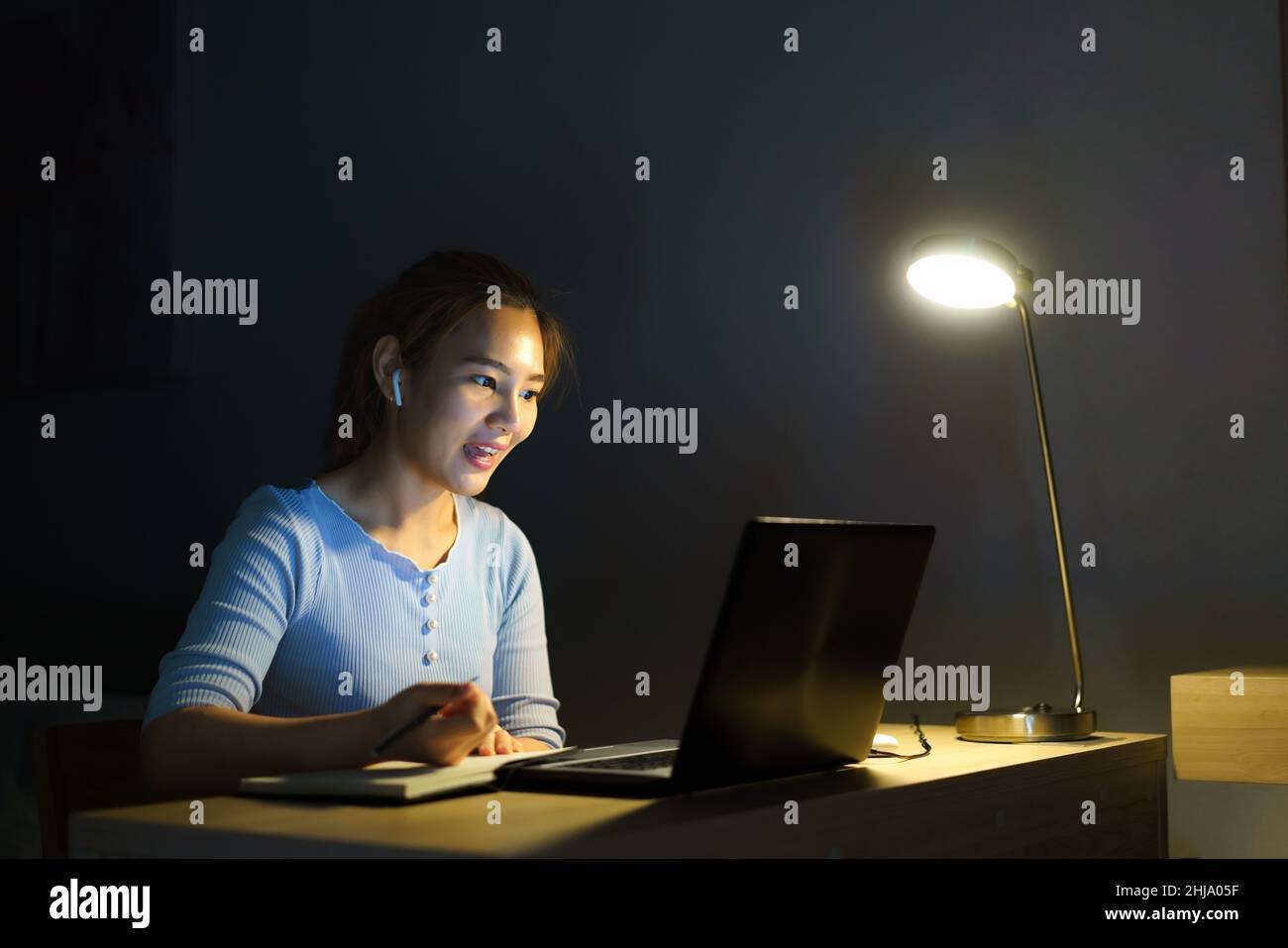 Les femmes asiatiques qui travaillent à la maison sont assises au travail avec leurs collègues ou leurs responsables par appel vidéo la nuit à la maison. Banque D'Images