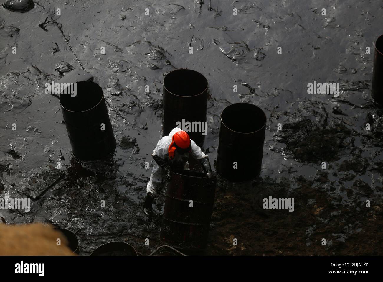 Ventanilla, Pérou.21st janvier 2022.Un homme en costume blanc travaille pour nettoyer le déversement de pétrole sur la plage de Cavero après environ 6 000 barils (159 litres chacun) de pétrole déversés pendant le déchargement d'un pétrolier à la raffinerie de la Pampla, propriété de la société espagnole d'énergie Repsol.Credit: GIAN Masko/dpa/Alay Live News Banque D'Images