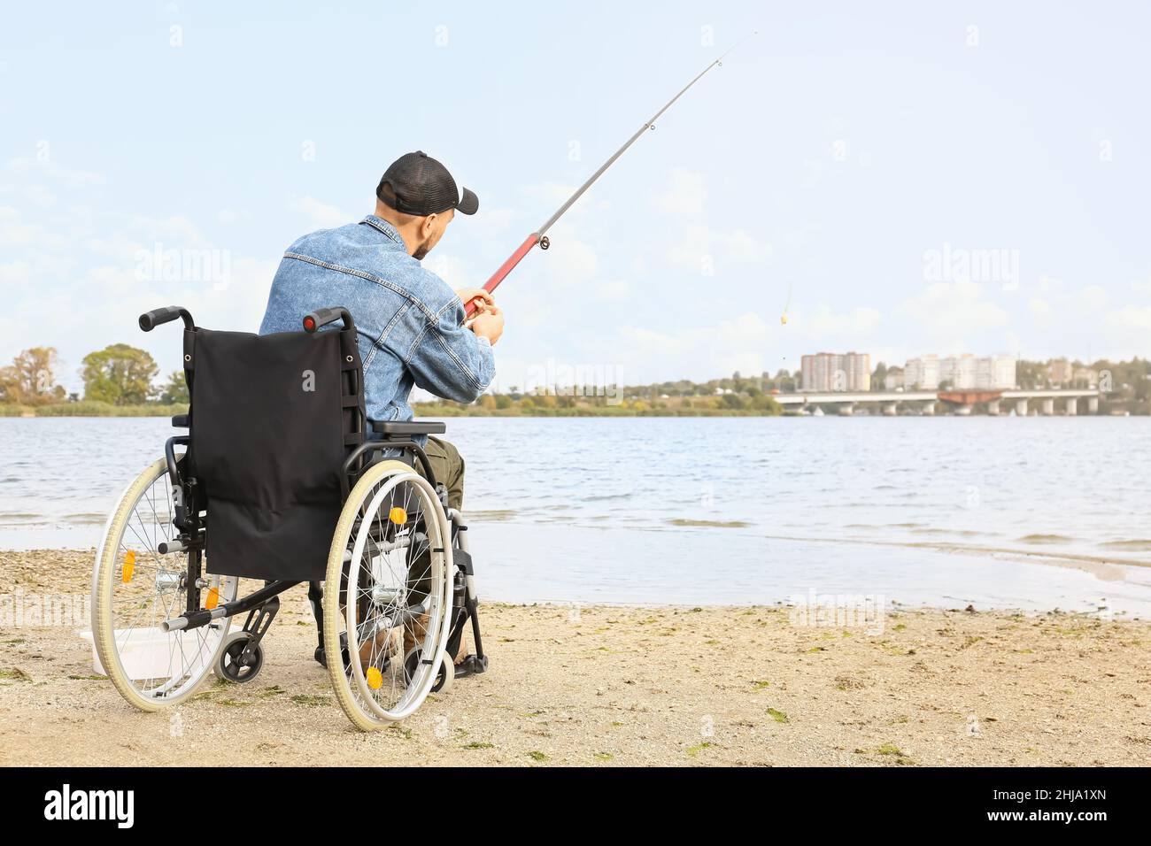 Homme en fauteuil roulant, pêche sur la rivière Banque D'Images