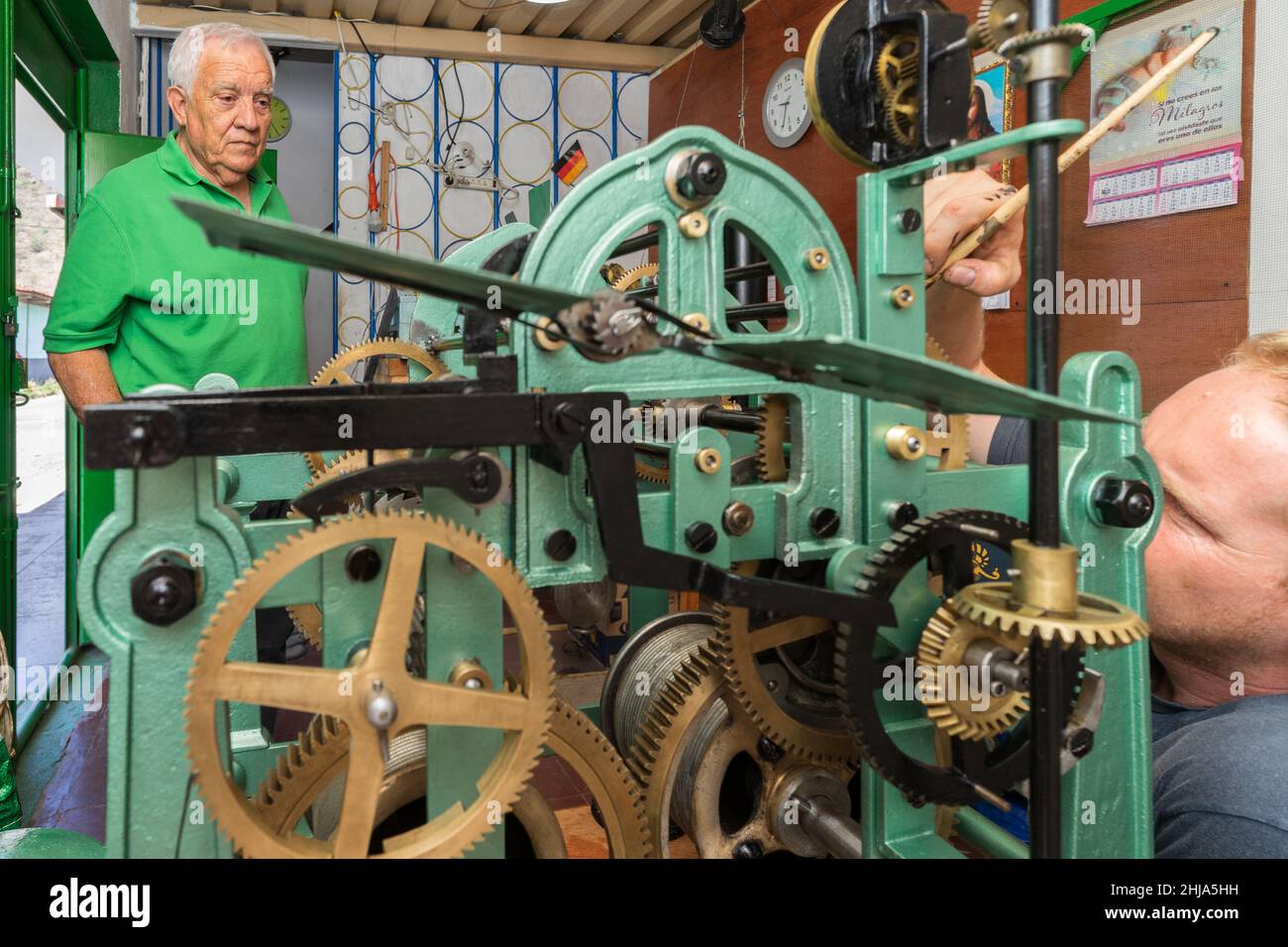 Magasin de réparation d'horloge: Le propriétaire d'atelier regarde un résident allemand du Nicaragua peinture des parties d'une horloge d'église à Jinotega, Nicaragua. Banque D'Images