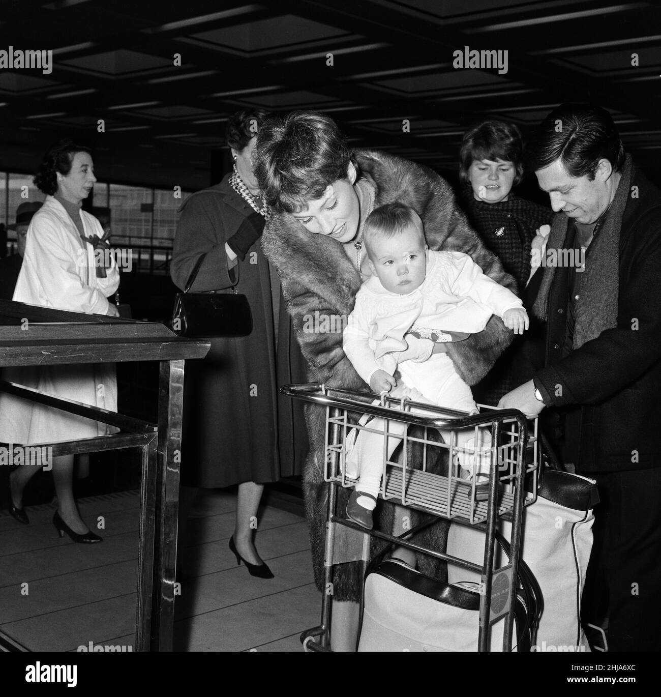 Julie Andrews et sa fille Emma quittent l'aéroport de Londres pour New York.La petite Emma avait la course de l'aéroport, et est allée à pied avec 'Cindy' un coolé.Elle a rencontré un petit garçon appelé Robin Coulson, âgé de 2 ans, et lui a dit de l'embrasser Au revoir avant d'être finalement rouée dans un chariot à bagages.18th février 1964. Banque D'Images