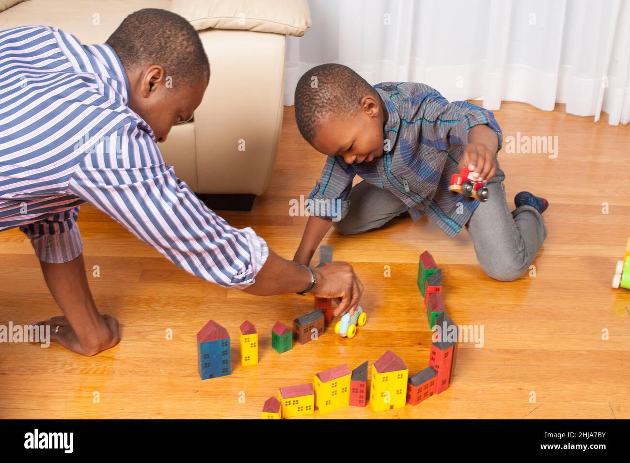 garçon de 4 ans jouant avec des blocs de construction en bois et des véhicules construisant la ville ou la rue avec l'aide du père Banque D'Images