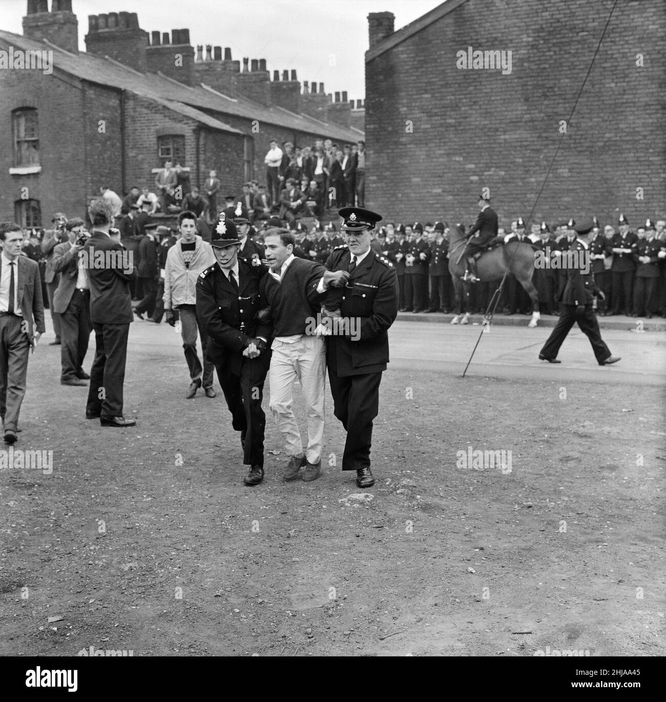 Sir Oswald Mosley se rend à Manchester pour participer à une marche organisée par son Union britannique des partisans des fascistes, dimanche 29th juillet 1962.Quand les quatre-vingt marcheurs se sont rassemblés, une foule en colère les a précipités et Mosley a disparu dans une vague de poings et de bottes volants et ses bannières de groupe ont été déchirées pour les tatouer.La police a brisé la foule des combats et a secouru Mosley, 65 ans, mais la marche s'est rapidement transformée en une émeute causant un mile de terreur avec des combats qui éclatent à quelques mètres.De nombreux marcheurs sont tombés avec des visages qui se saignent et des vêtements déchirés.Les autres ont été pillés avec des pierres, des pièces de monnaie, des choux, des tomates A. Banque D'Images Sir Oswald Mosley se rend à Manchester pour participer à une marche organisée par son Union britannique des partisans des fascistes, dimanche 29th juillet 1962.Quand les quatre-vingt marcheurs se sont rassemblés, une foule en colère les a précipités et Mosley a disparu dans une vague de poings et de bottes volants et ses bannières de groupe ont été déchirées pour les tatouer.La police a brisé la foule des combats et a secouru Mosley, 65 ans, mais la marche s'est rapidement transformée en une émeute causant un mile de terreur avec des combats qui éclatent à quelques mètres.De nombreux marcheurs sont tombés avec des visages qui se saignent et des vêtements déchirés.Les autres ont été pillés avec des pierres, des pièces de monnaie, des choux, des tomates A. Banque D'Images