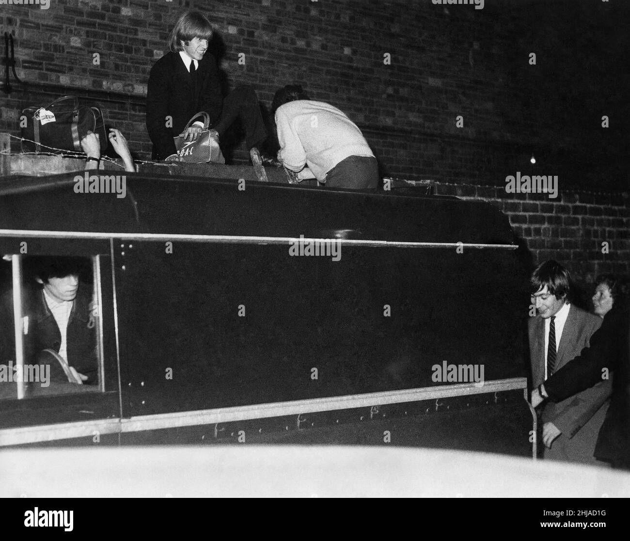 Brian Jones, sur le mur Mick Jagger avec de retour à la caméra Charlie Watts derrière Land Rover et Bill Wyman devant Rover alors que les Rolling Stones tentent d'entrer dans un concert.Septembre 1964 Banque D'Images