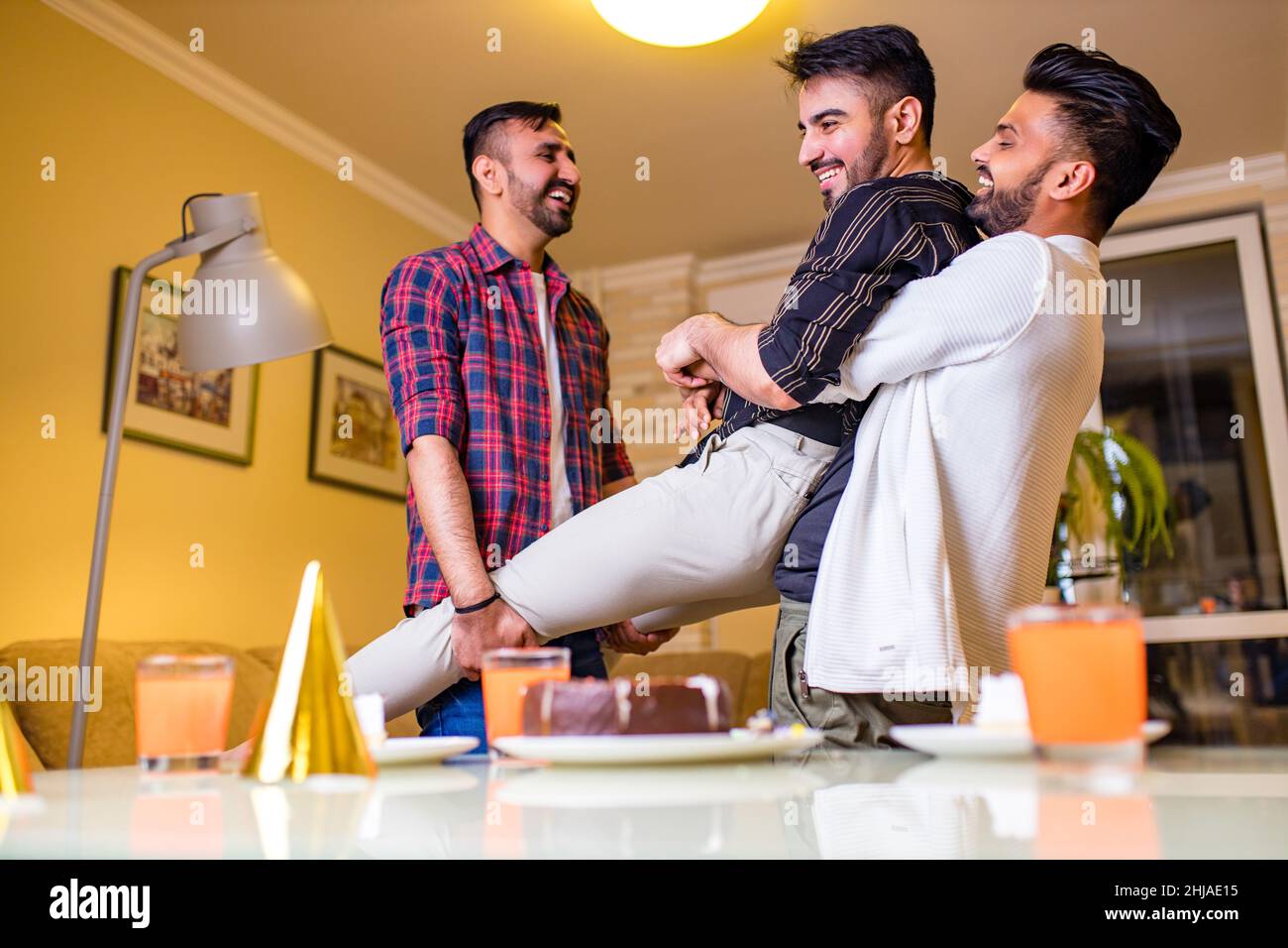Un homme arabe excité prêt à souffler des bougies sur le gâteau lors de la fête d'anniversaire avec des amis heureux dans la maison Banque D'Images