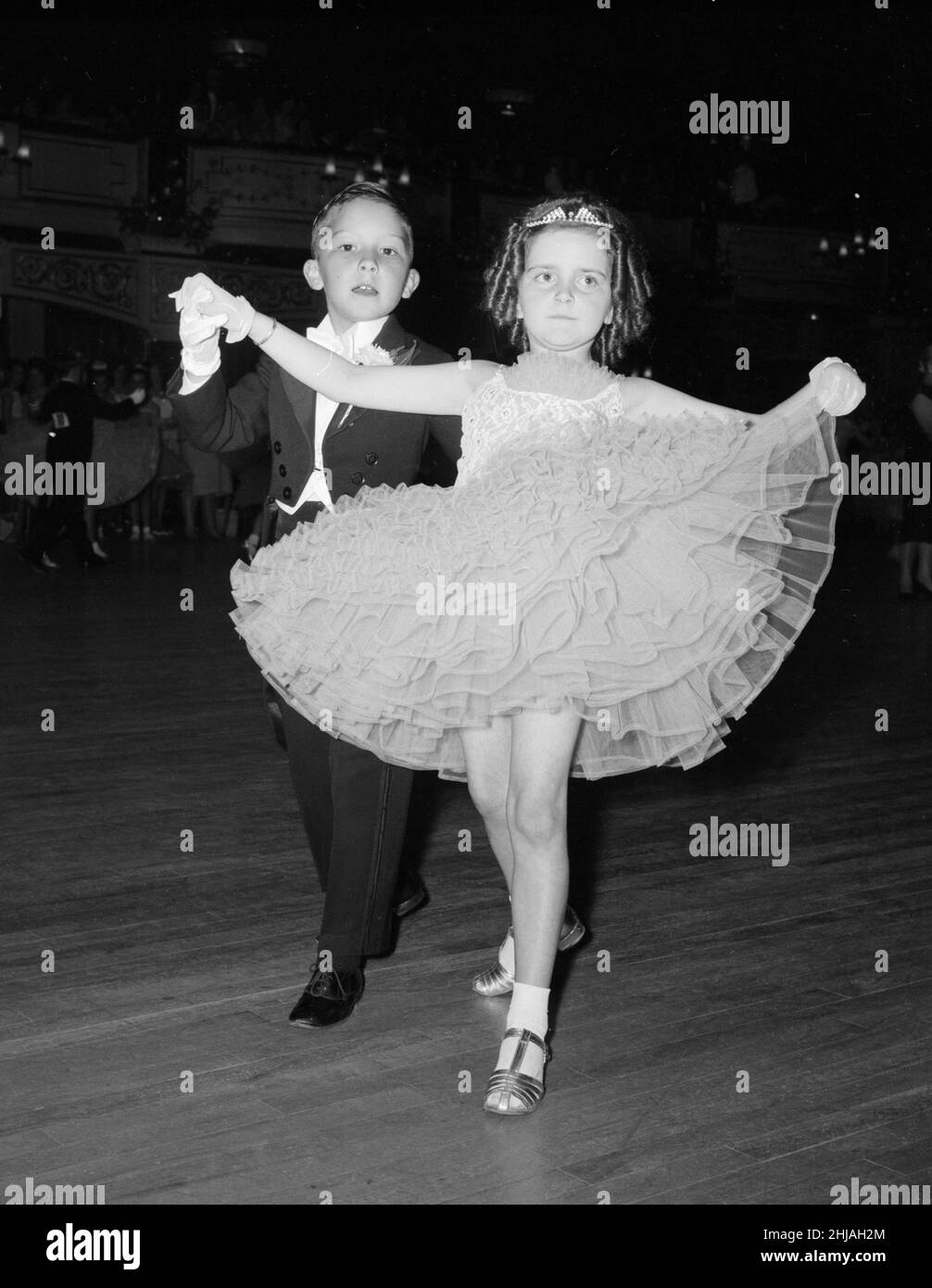 Ralph Farish, huit ans, portant un costume de soirée formel, prend la main de sa partenaire Sandra Harrison dans sa robe de balle de style crinoline alors qu'ils prennent la parole pendant le concours junior de danse Old Time au Palais Hammersmith.4th juin 1963. Banque D'Images