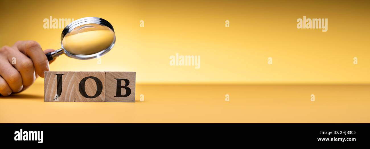 La main de la personne regarde les blocs de travail à travers la loupe sur le bureau Banque D'Images