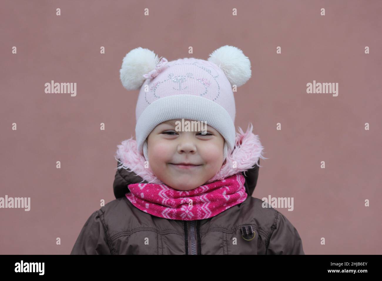 Portrait de l'enfant en tissu chaud en hiver en regardant de côté sur fond violet Banque D'Images