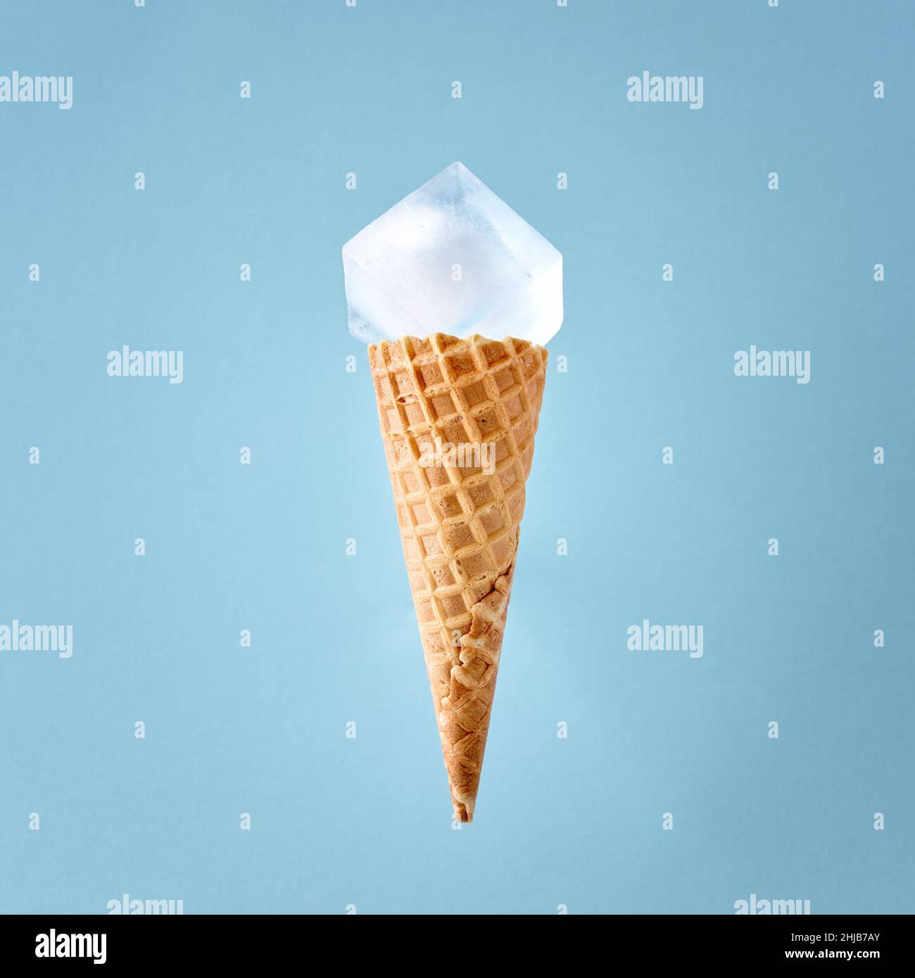 Cornet de gaufres à la crème glacée avec un grand cube de glace sur fond bleu.Concept alimentaire d'été froid minimal.Pose à plat. Banque D'Images