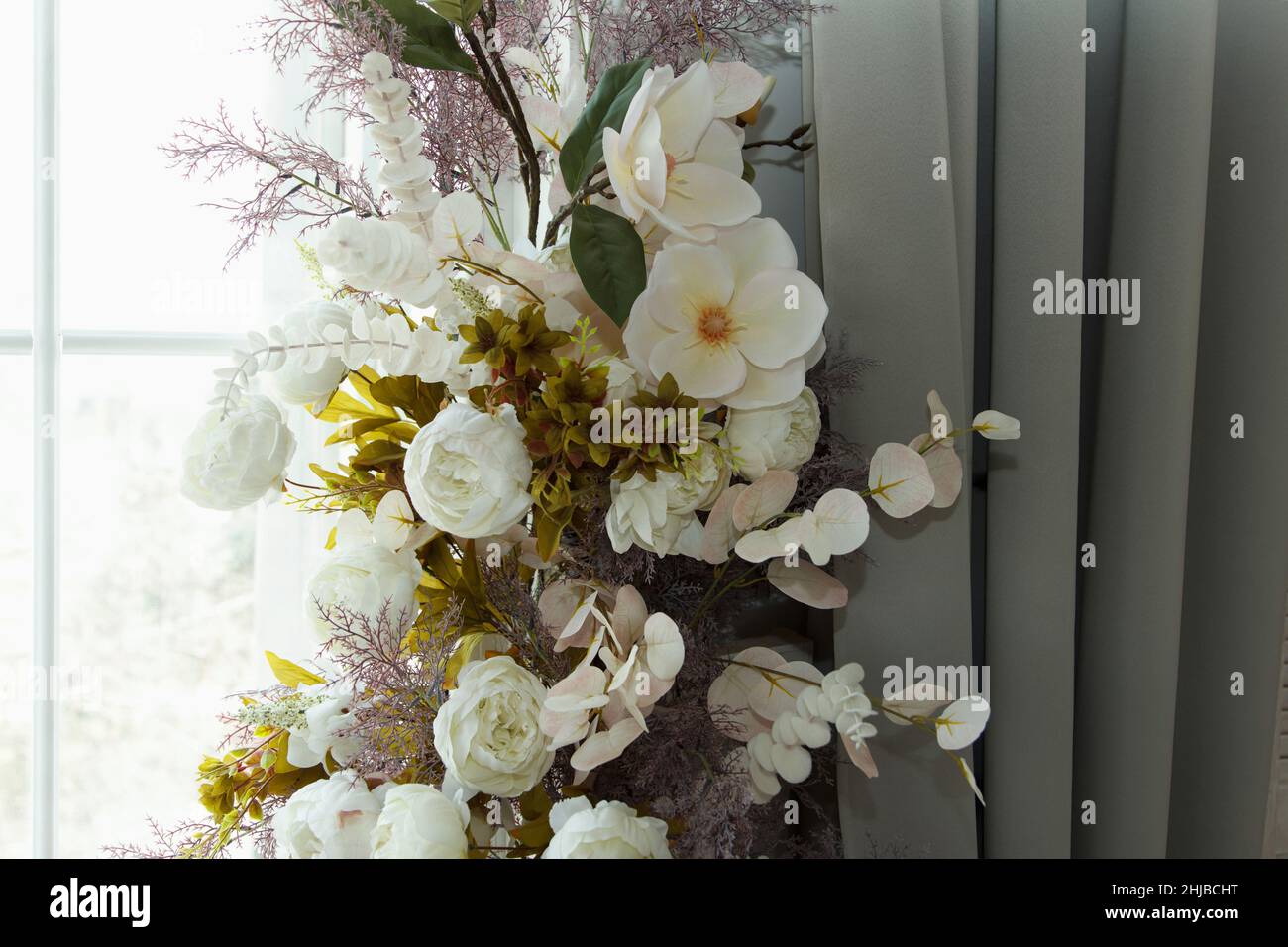Bouquet de belle fleur décorative blanche en matériau et en plastique accroché près de la fenêtre comme partie de l'intérieur Banque D'Images