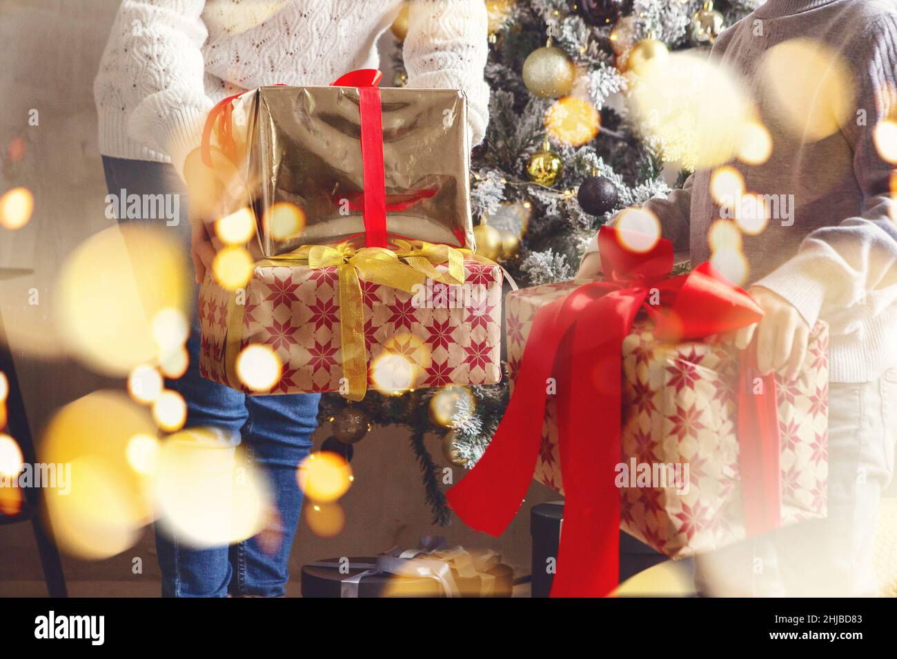 Photo courte de femme et de petit garçon tenant une pile de cadeaux de Noël ou du nouvel an pour les membres de la famille et les membres de la famille tout en se tenant près d'un sapin décoré Banque D'Images
