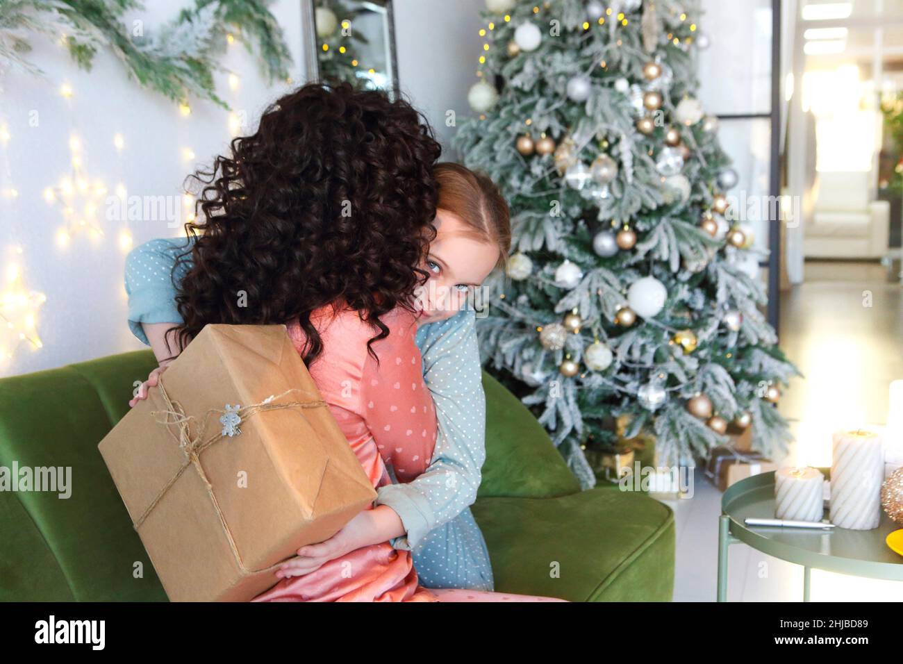 Mère et fille en pyjama embrassant tout en échangeant des cadeaux de Noël le matin, foyer sélectif.Maman et enfant avec des cadeaux de Noël au hom Banque D'Images