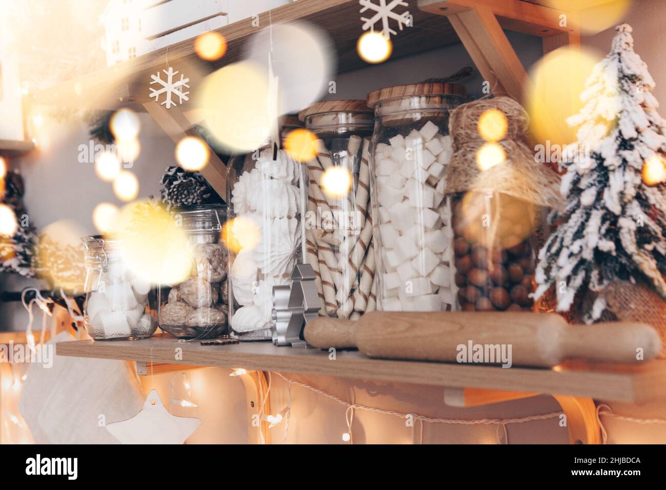Comptoir de magasin de bonbons ou de café décoré de décorations de Noël pendant Noël, étagères en bois avec pots en verre remplis de bonbons disposés en rangée Banque D'Images