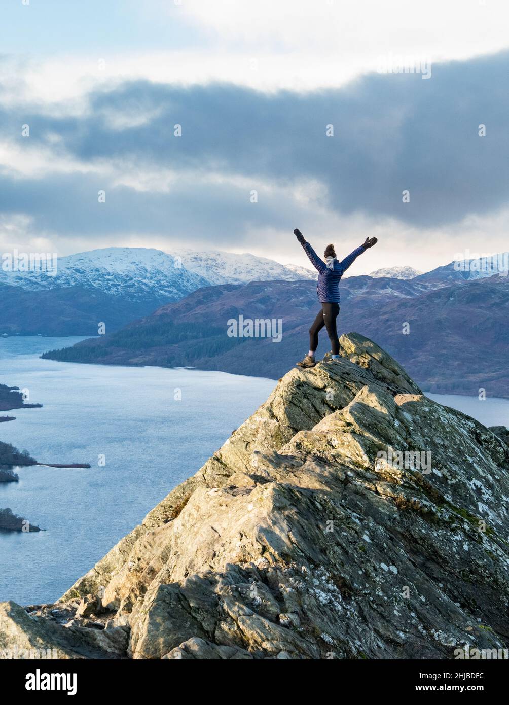 Marcheur féminin au sommet de Ben A'an en hiver, surplombant le Loch Katrine, le Loch Lomond et le parc national des Trossachs, Écosse, Royaume-Uni Banque D'Images