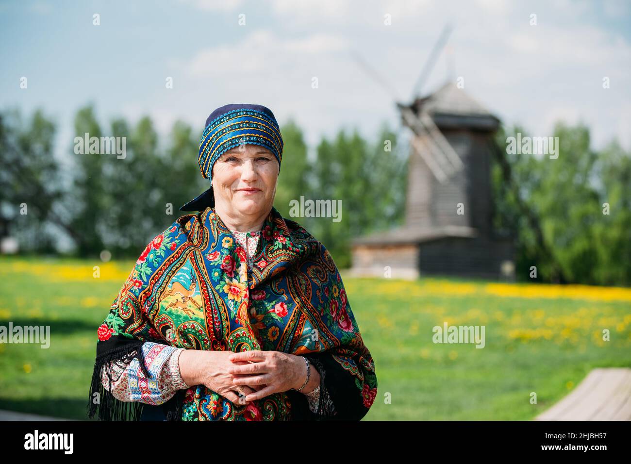 Femme russe en robe et foulard russes traditionnels sur le fond d'un ancien moulin en bois. Banque D'Images