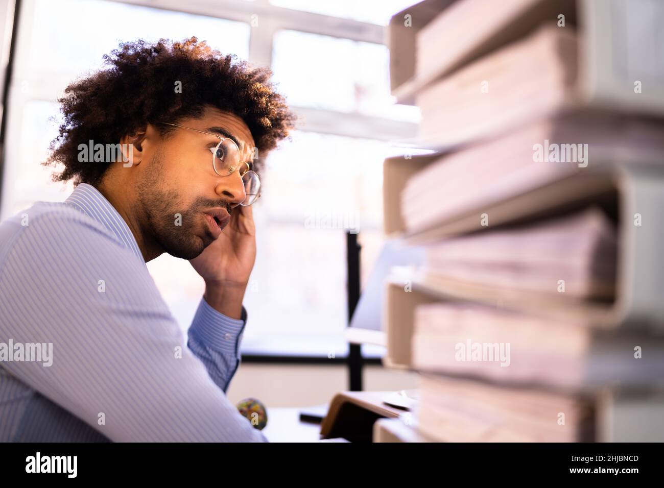 Un jeune homme d'affaires fatigué de calculer l'impôt à la réception au bureau Banque D'Images