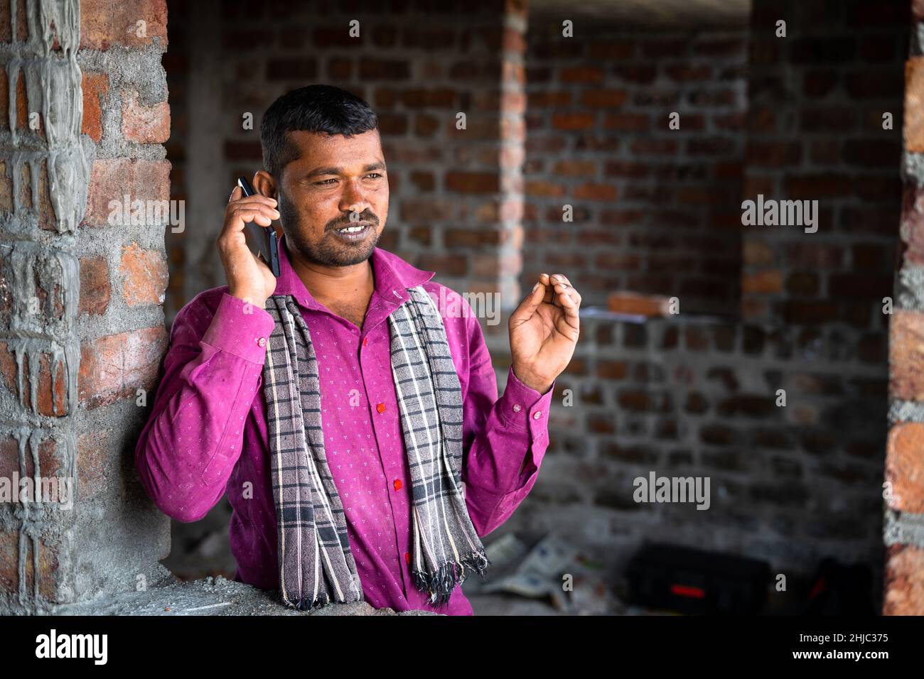 Joyeux travail de construction souriant parlant sur téléphone mobile - concept de réseau de communication et de technologie Banque D'Images