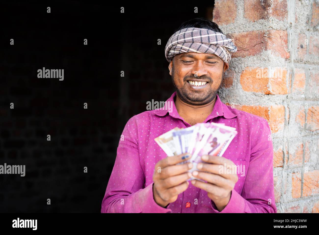 joyeux jeune indien pari quotidien ou ouvrier de construction comptant l'argent sur le lieu de travail - concept de la rémunération d'emploi de col bleu, bancaire et financier. Banque D'Images