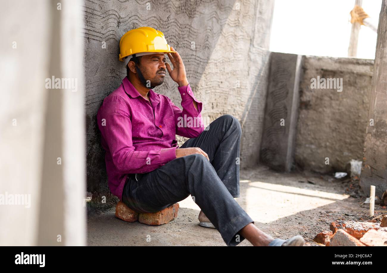 Travailleurs de construction inquiets et réfléchis assis sur le site - concept de perte d'emploi, de délabrement et de solitude. Banque D'Images