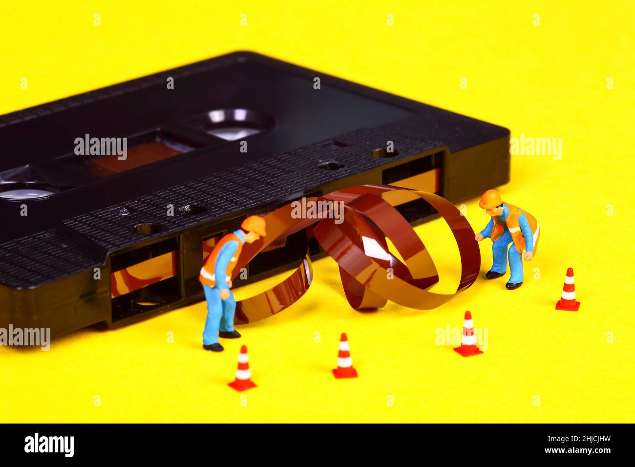 Image conceptuelle d'ouvriers miniatures inspectant une cassette rétro ancienne qui s'est décomposée après un bourrage de bande Banque D'Images