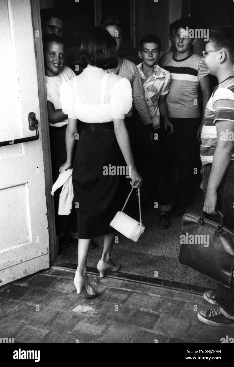 Jeune fille arrivant pour le premier jour à l'école secondaire étant gawed par les garçons. Banque D'Images