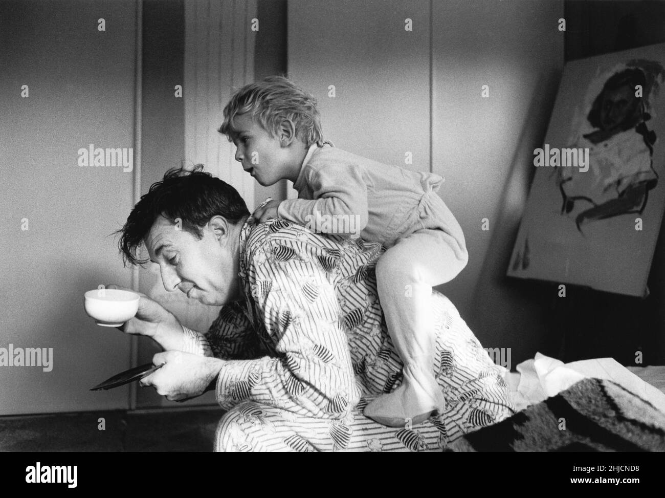 Photographie en noir et blanc d'un garçon grimpant sur son père en début de matinée.Photographie prise pour le Ladies' Home Journal vers 1963. Banque D'Images