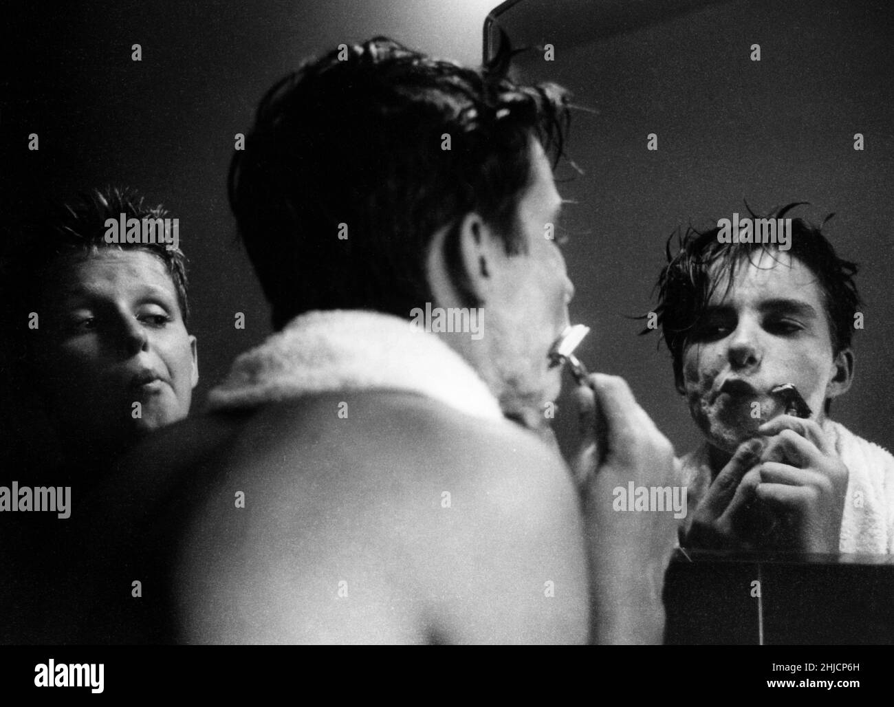Un jeune garçon regardant son frère aîné se raser avec soin.Vers 1958. Banque D'Images