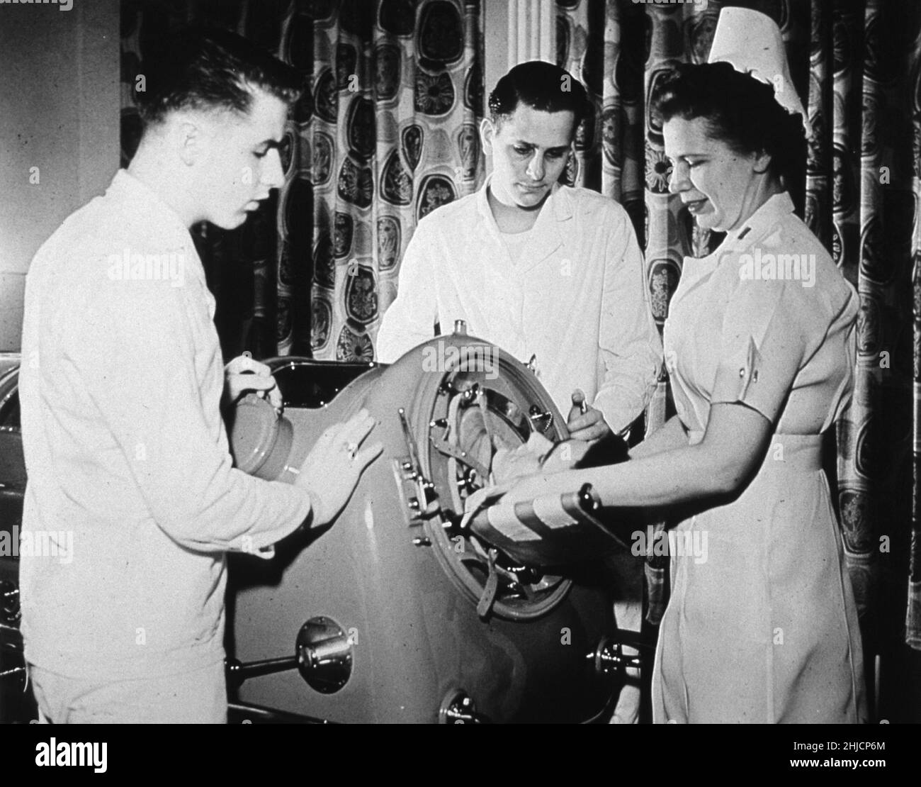 Une infirmière et deux corpmen s'occupent d'un patient de poliomyélite dans un poumon de fer.Armée des États-Unis, 1949. Banque D'Images