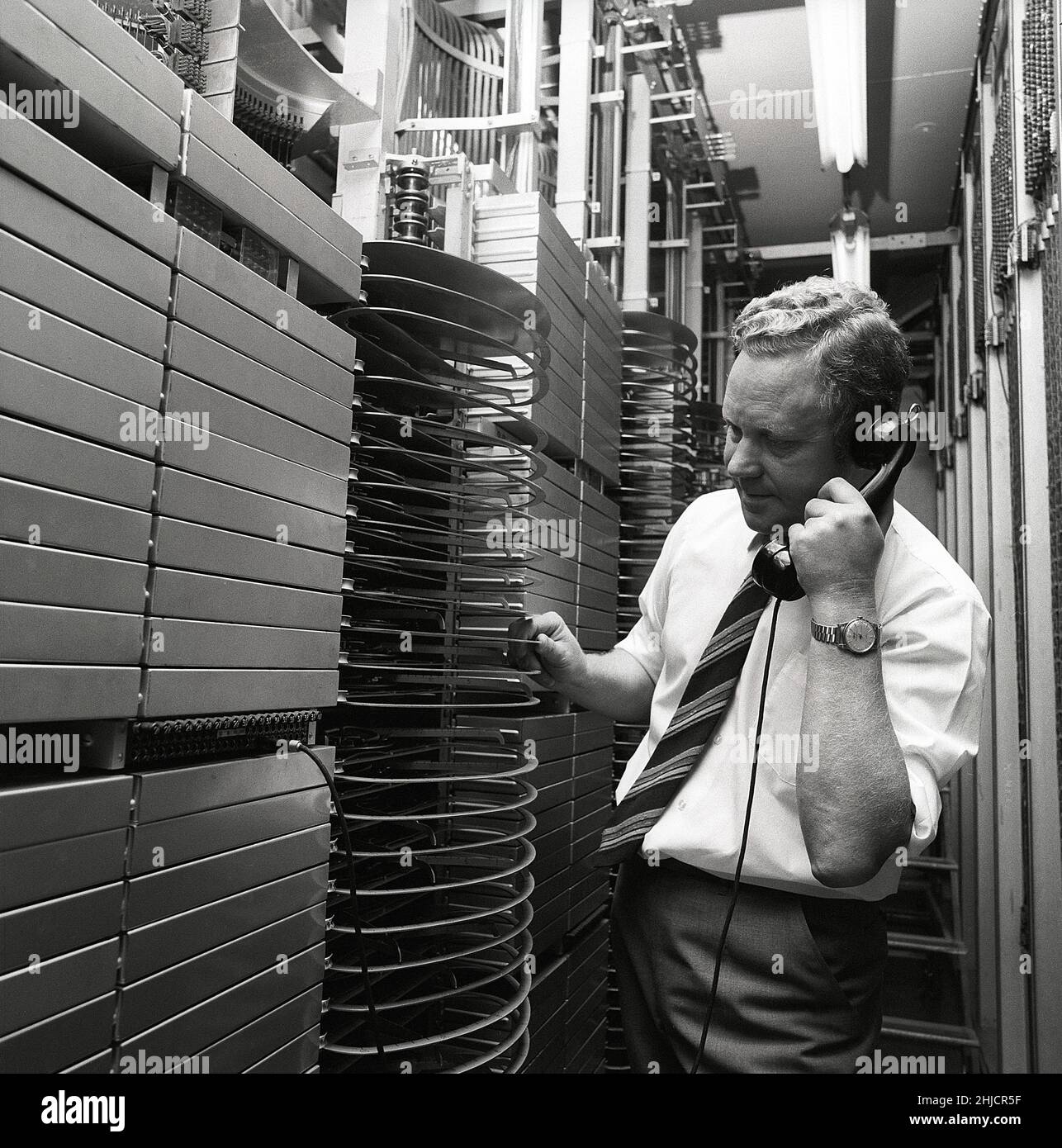 Téléphonie dans le 1970s.Homme dans une pièce avec un tableau de commutation automatique reliant les appels via un dispositif mécanique qui connecte les pièces d'appel et de réception.Le fabricant est LM Ericsson.Suède 1971 Kristoffersson ref. Ed Banque D'Images