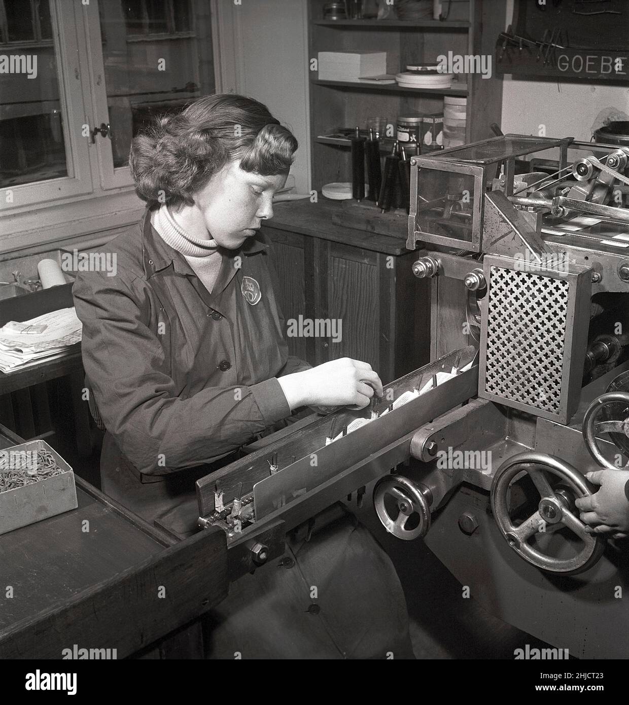 Production de timbres-poste en 1950s.Une jeune femme au timbre suédois printworks du poste suédois à la machine produisant des livrets de timbres.Suède 1951 Kristoffersson réf. bc46-8 Banque D'Images