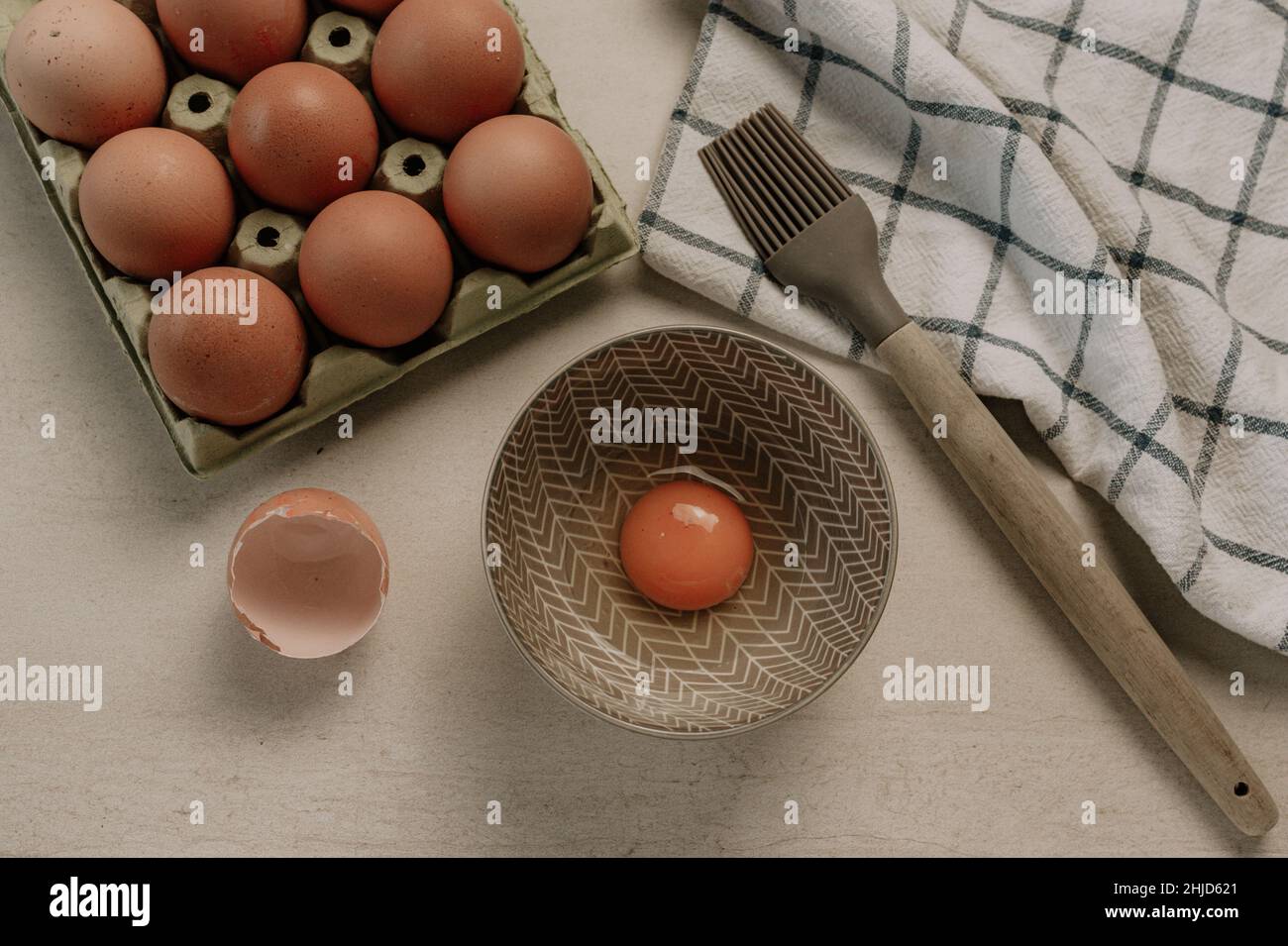 Œufs, brosse à pâtisserie et serviette de cuisine sur une table en marbre.Application de l'œuf liquide Banque D'Images