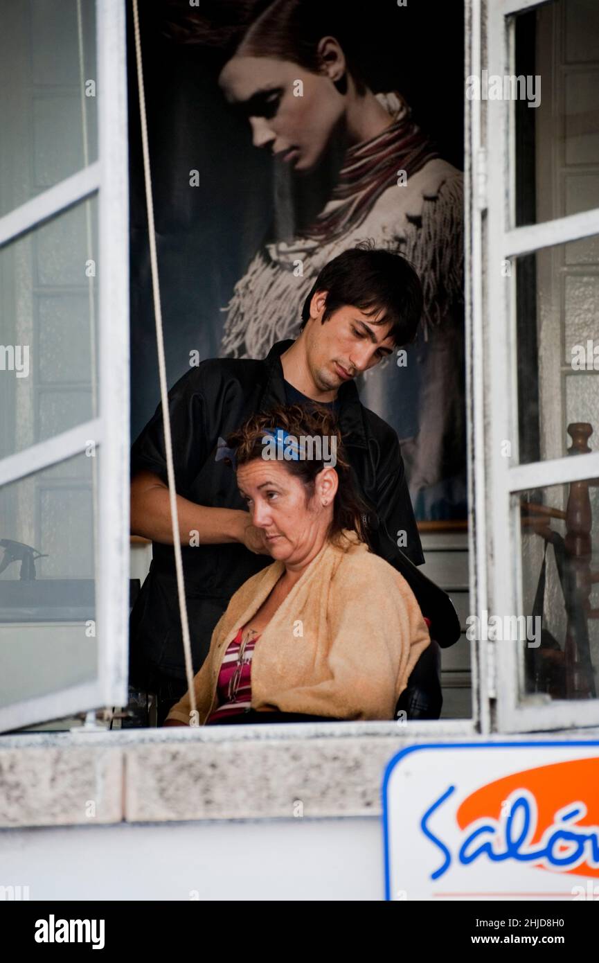 Le coiffeur masculin fait les cheveux de la femme dans un salon pour les femmes en face de l'hôtel Havana libre à la Havane, Cuba. Banque D'Images