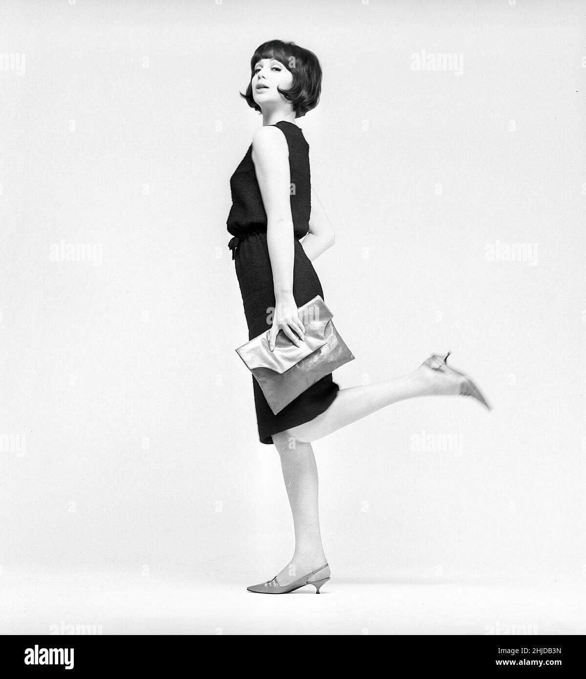 Dans le 1960s.Un modèle dans un ensemble typique de 1960s photographié dans un studio.Une robe populaire noire à la hauteur opportune juste en dessous de hauteur de Kneeheight.Suède 1960s Kristoffersson réf. CV21-9 Banque D'Images