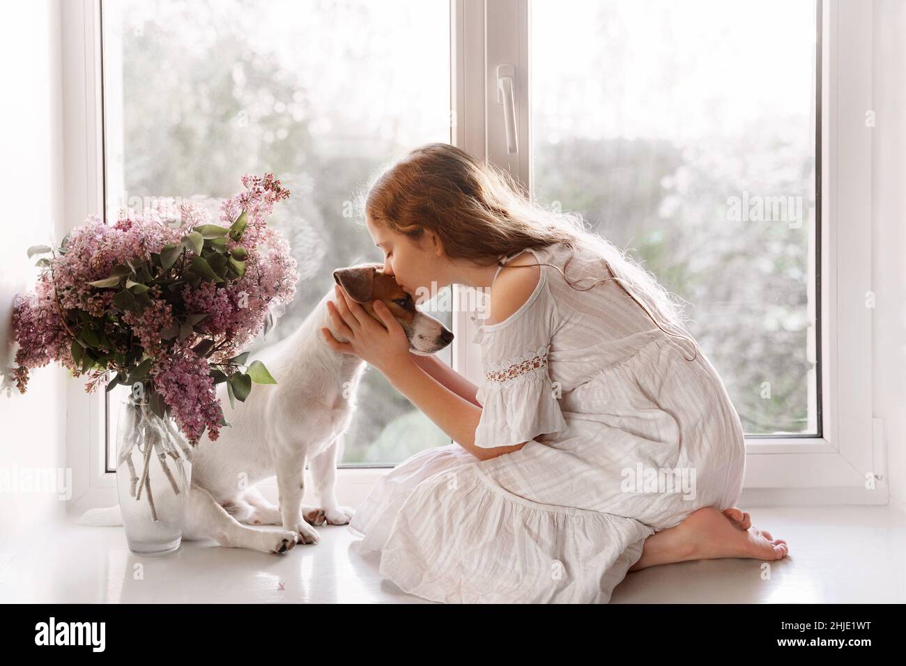 Une petite fille adorable embrasse un chien.Deux amis assis sur la fenêtre.Amitié, soins, concept d'enfance heureuse. Banque D'Images