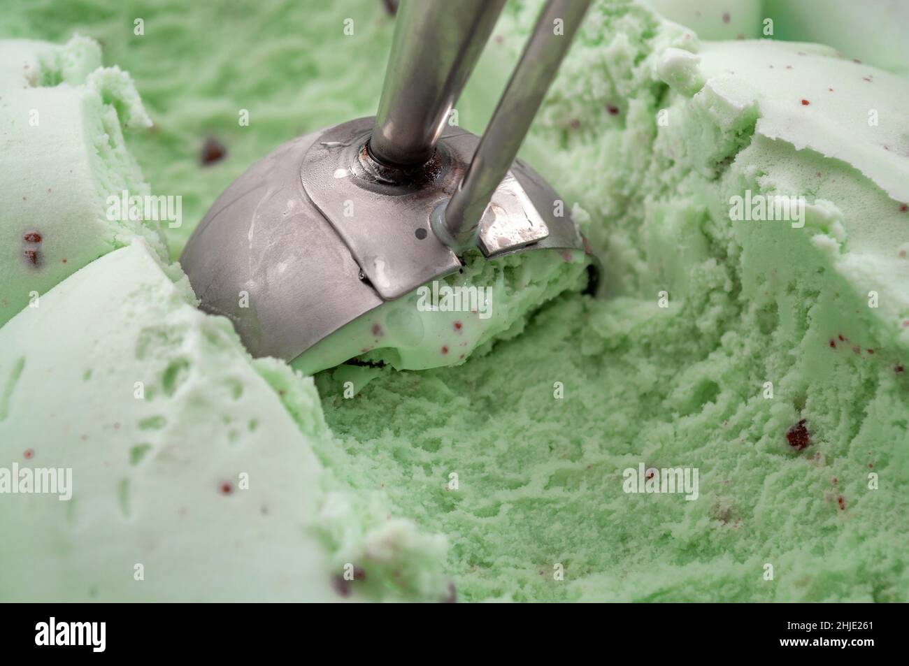Rafraîchissement délicieux et soin rafraîchissant de l'été avec une pelle en métal qui ramasse une boule verte de pistache lisse ou de crème glacée à la menthe Banque D'Images