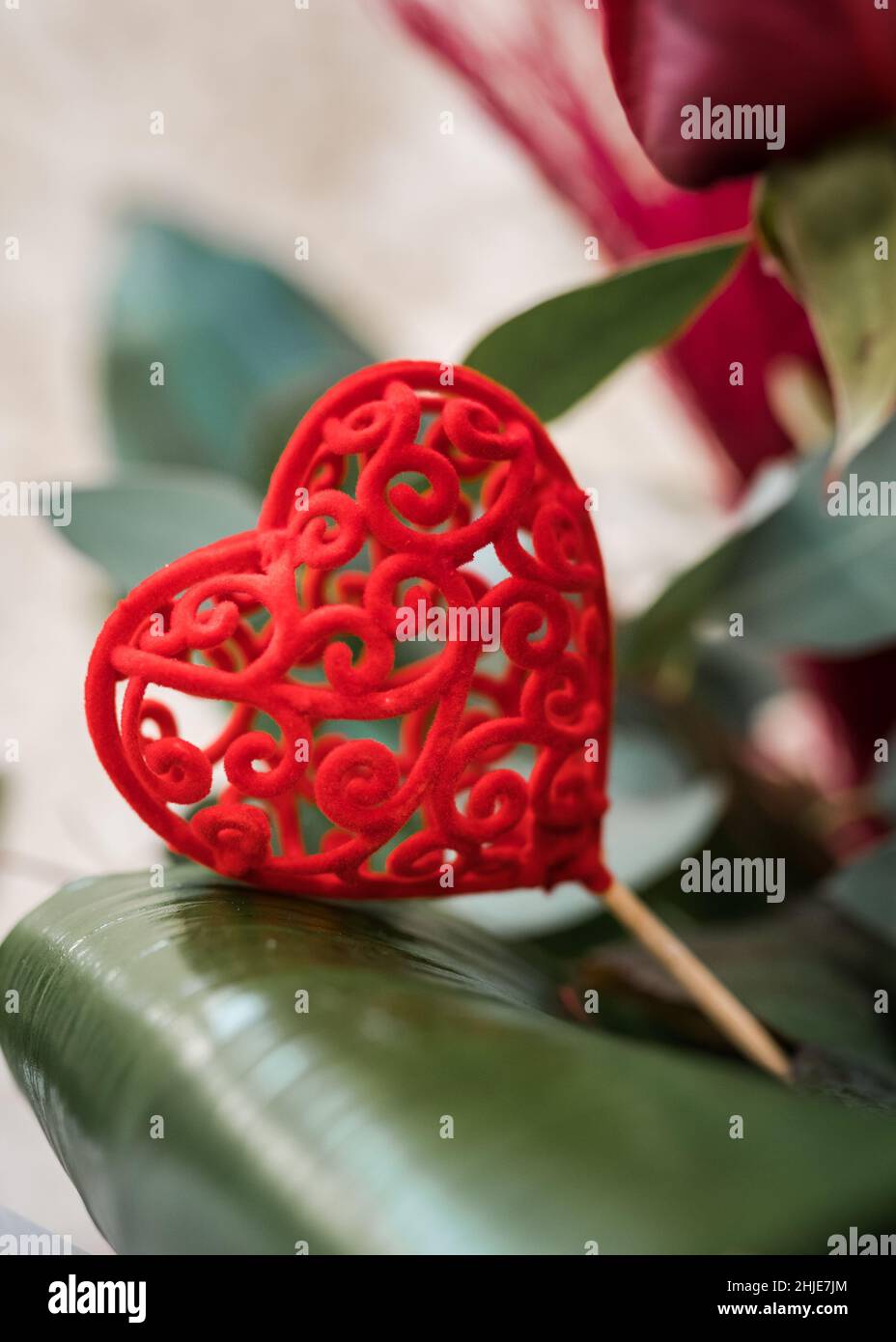 Superbe Saint Valentin rouge amour coeur décoration dans bouquet de fleurs pour le cadeau à l'être aimé.Forme ornée sur un motif coloré brillant bâton. Banque D'Images