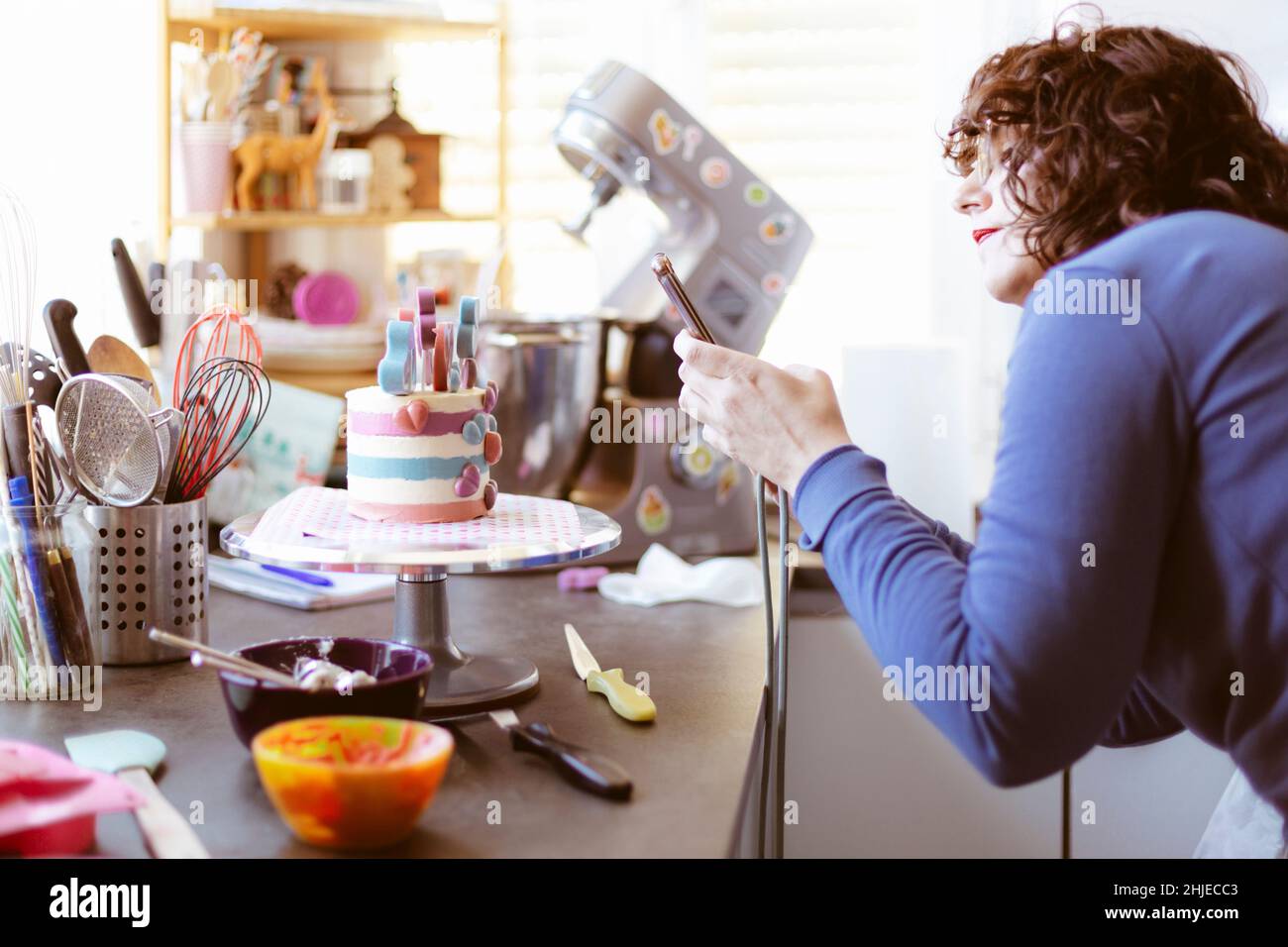 Femme caucasienne à la maison prenant une photo d'un gâteau avec son téléphone portable.Mise au point sélective. Banque D'Images