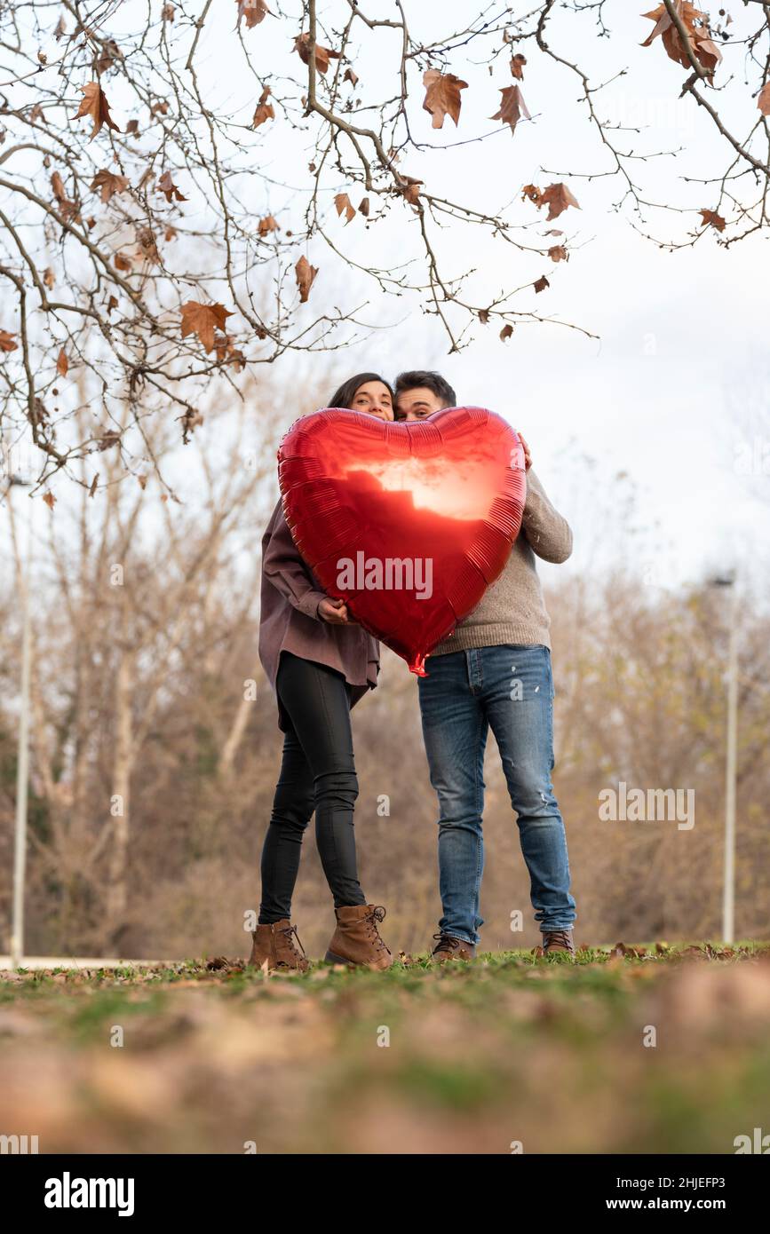 Jeune couple célébrant la Saint-Valentin en tenant une montgolfière en forme de cœur Banque D'Images