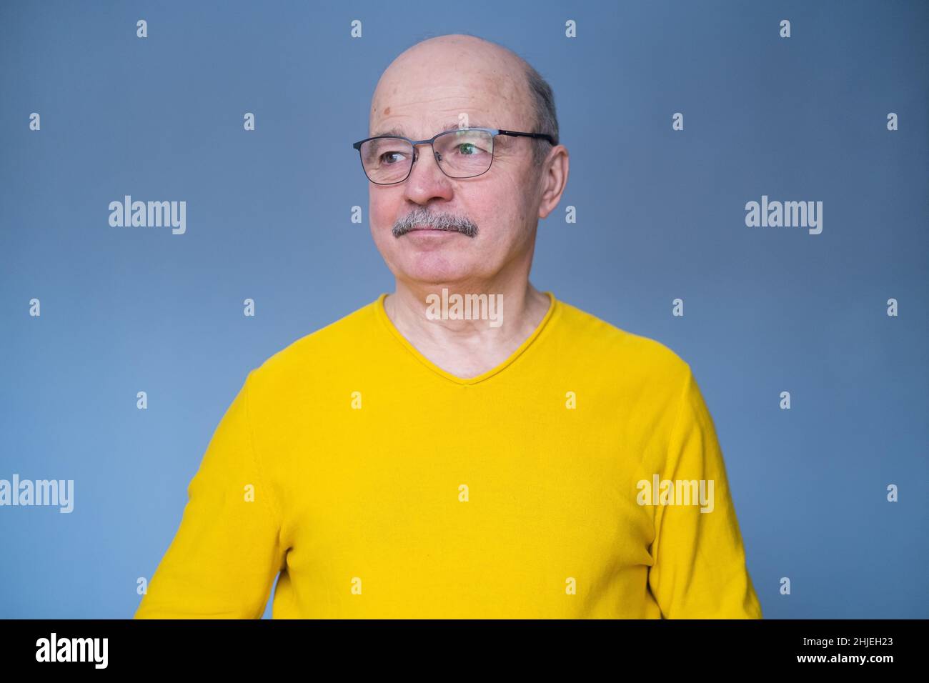 Homme hispanique senior essayant ses nouvelles lunettes.Studio tourné sur fond bleu Banque D'Images