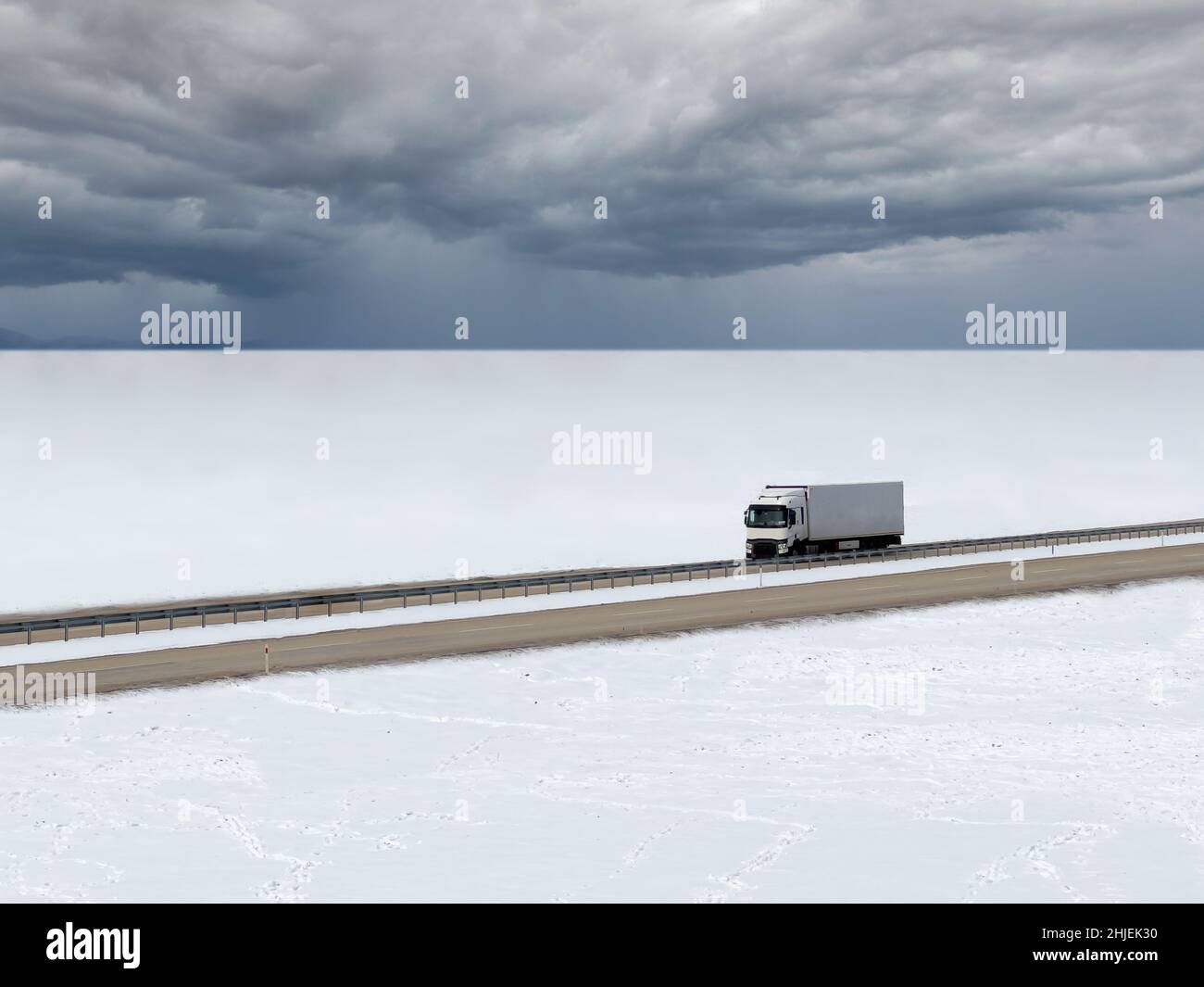 Camion roulant sur une route enneigée par une journée hivernale enneigée Banque D'Images