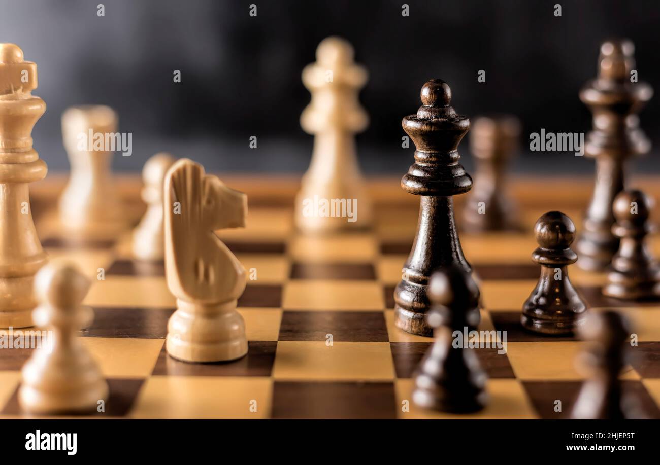 Jeu d'échecs avec des pièces en bois noir et blanc sur un échiquier en bois. Banque D'Images