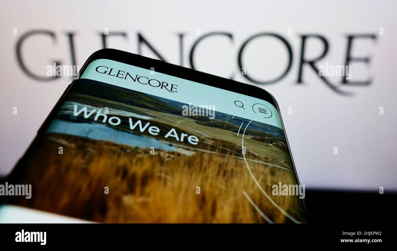 Téléphone mobile avec le site Web de la société de commerce de marchandises Glencore plc à l'écran devant le logo de l'entreprise.Faites la mise au point dans le coin supérieur gauche de l'écran du téléphone. Banque D'Images