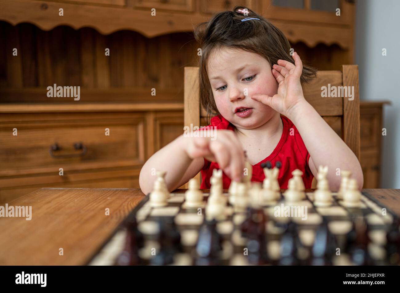 Une petite fille intelligente jouant aux échecs. Banque D'Images