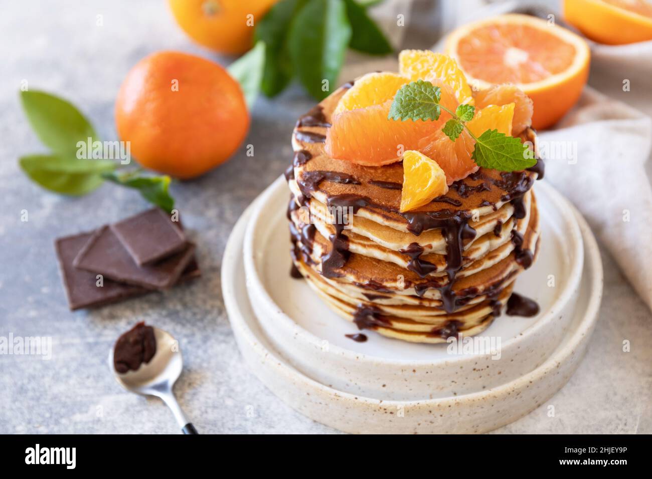 Fête du Pancake, petit déjeuner sain.Délicieuses crêpes américaines maison à la banane avec chocolat et orange rouge sur fond de pierre grise. Banque D'Images